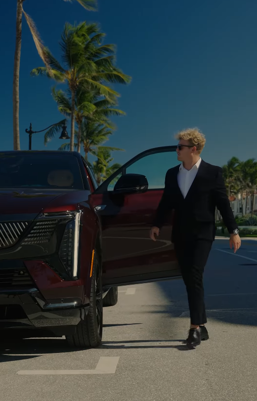 Creator stepping out of a Cadillac Escalade IQ with palm trees in the background